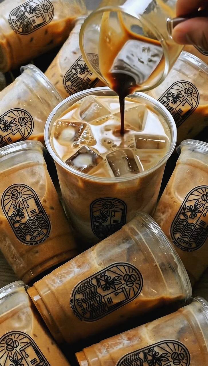 Espresso being poured into an iced latte in a Koffie cup